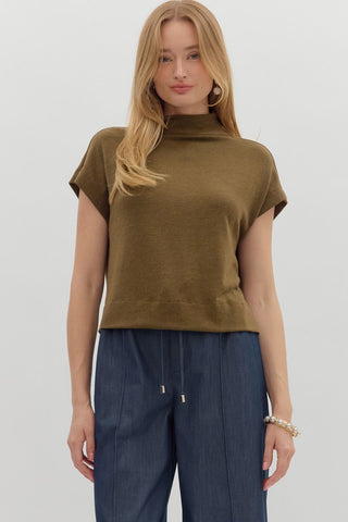 Woman wearing a brown sleeveless top and blue pants on a white background
