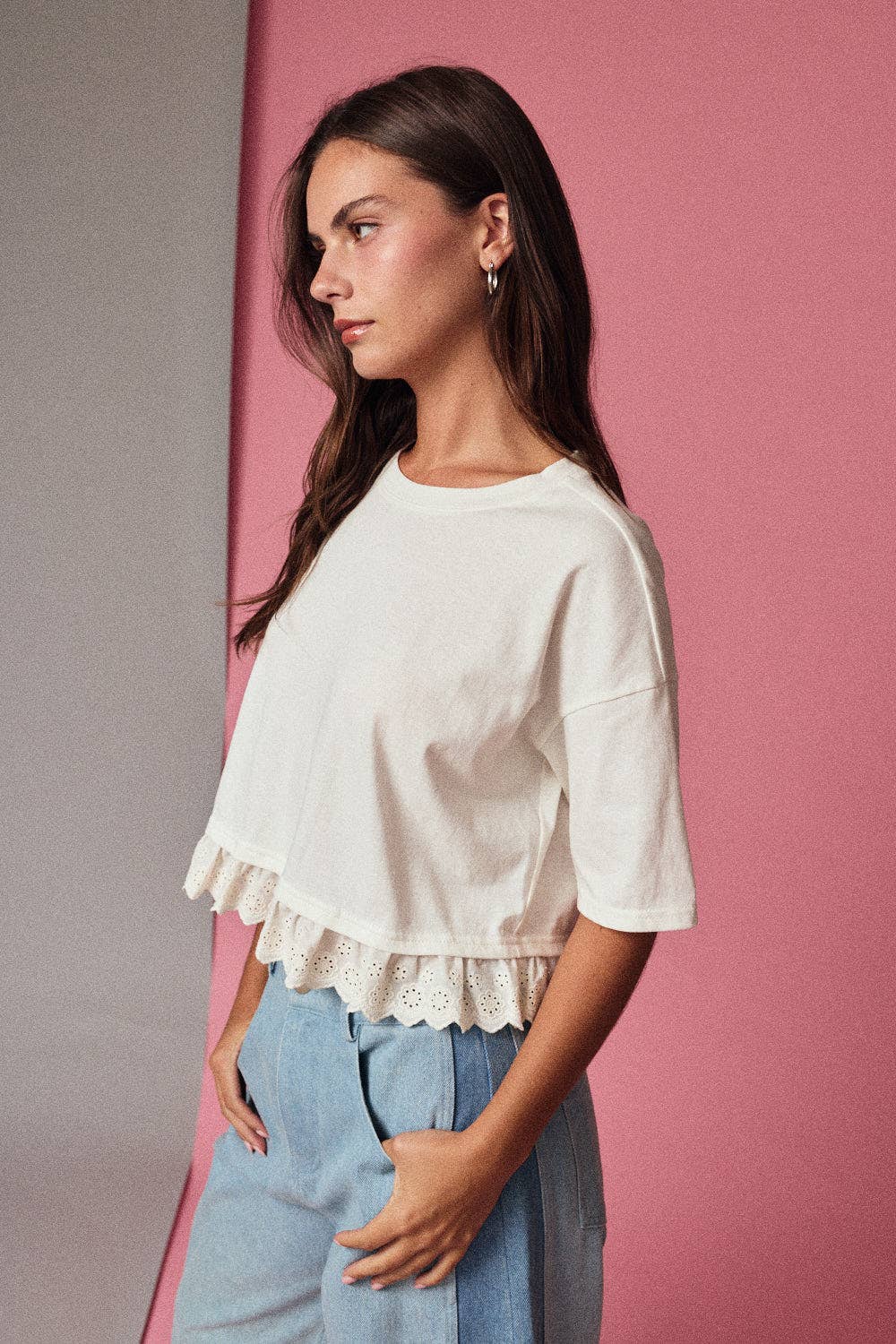 Woman wearing a white blouse with ruffled details against a pink background