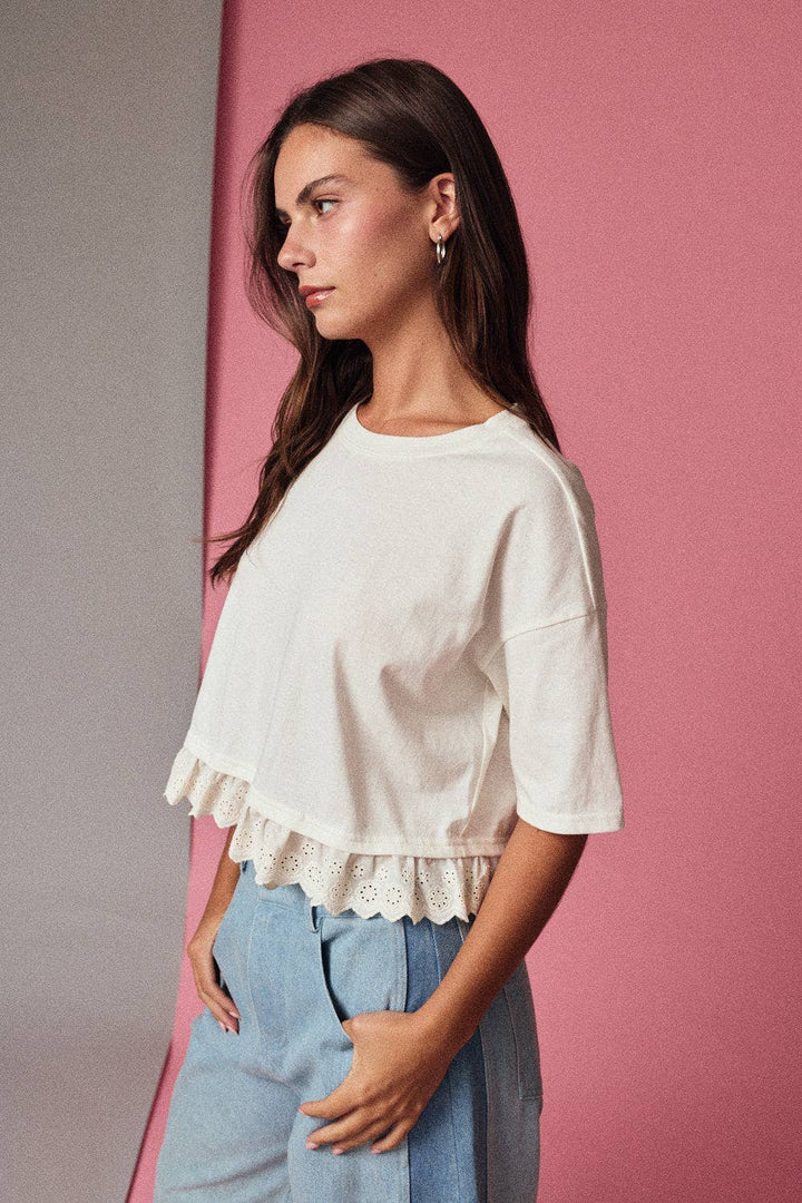 Woman wearing a white blouse with ruffled details against a pink background