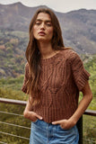 Woman wearing a brown knitted sweater with mountains in the background