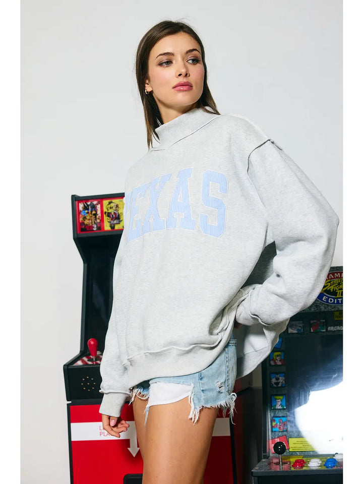 Woman wearing a sweatshirt with Texas appliqued on it. 