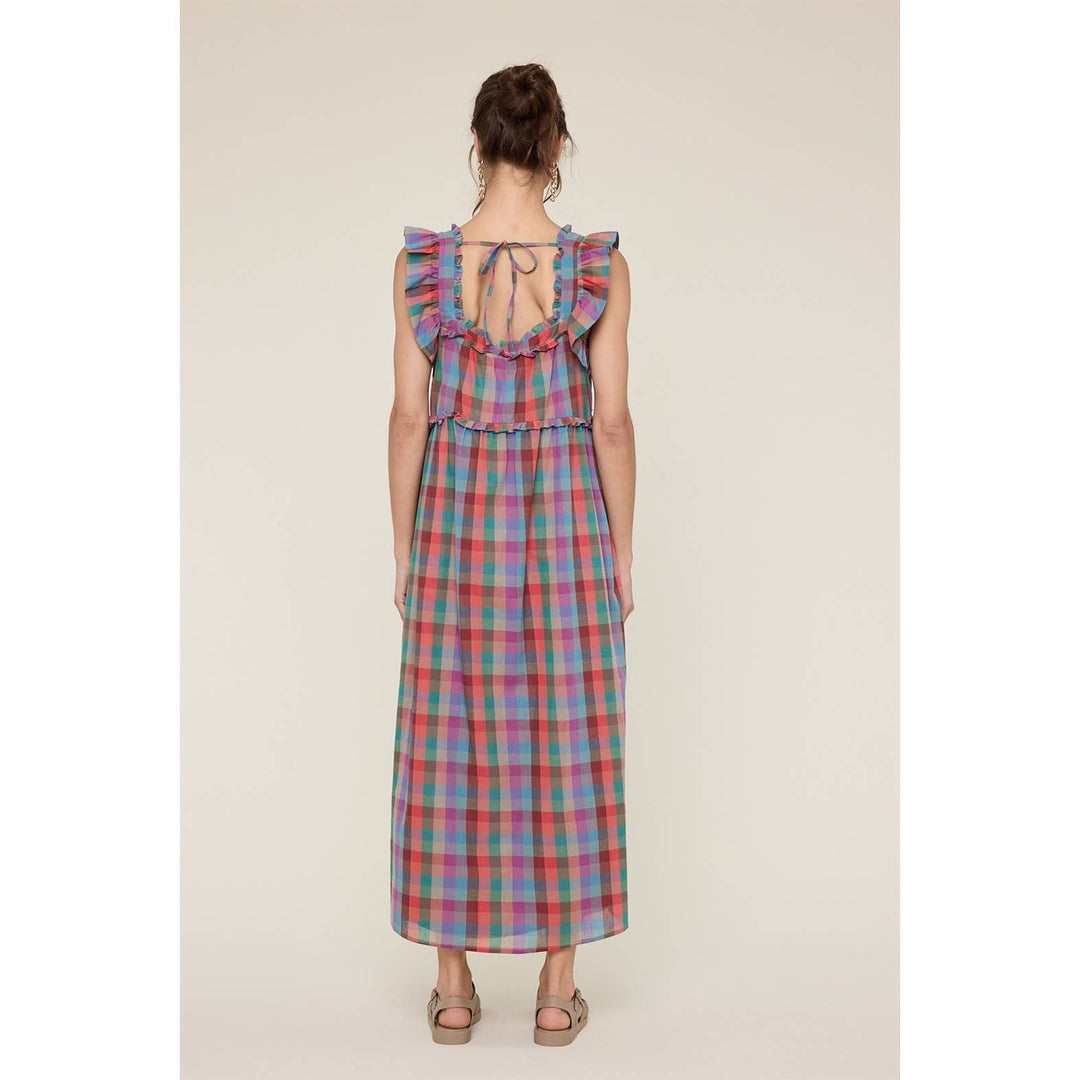 Woman wearing a colorful plaid dress with ruffled straps on a beige background