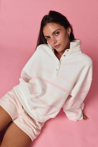Woman wearing a white sweatshirt with pink accents on a pink background