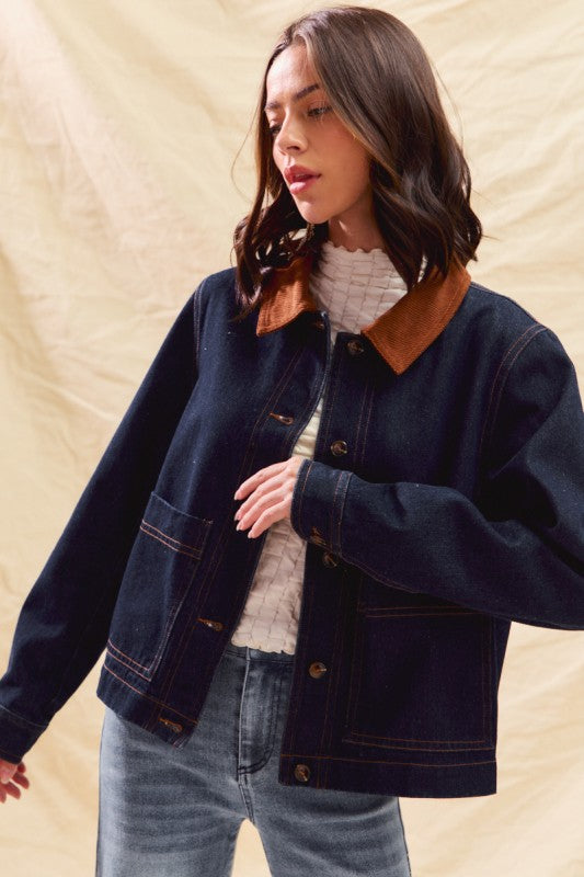 Woman wearing a dark denim jacket over a white sweater with a beige background