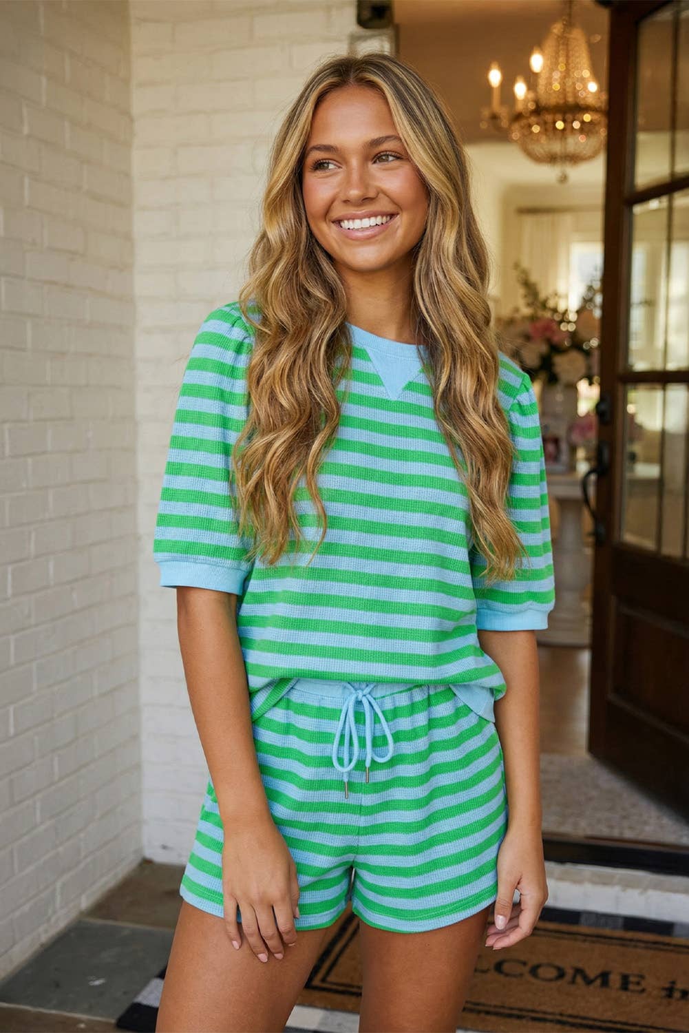 Woman wearing a green and white striped outfit standing in a doorway.