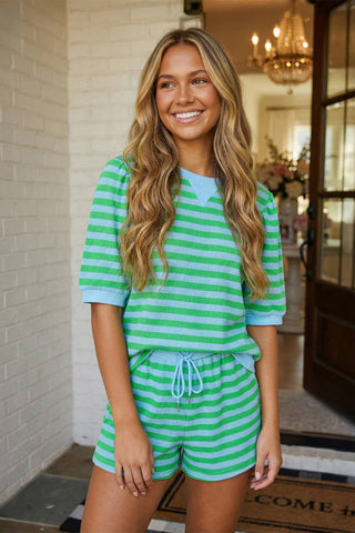 Woman wearing a green and white striped outfit standing in a doorway.