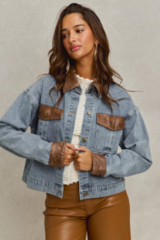 Woman wearing a denim jacket with brown accents on a neutral background