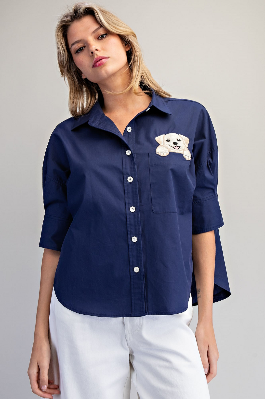 Woman wearing a navy blue shirt with a small white dog design on a gray background