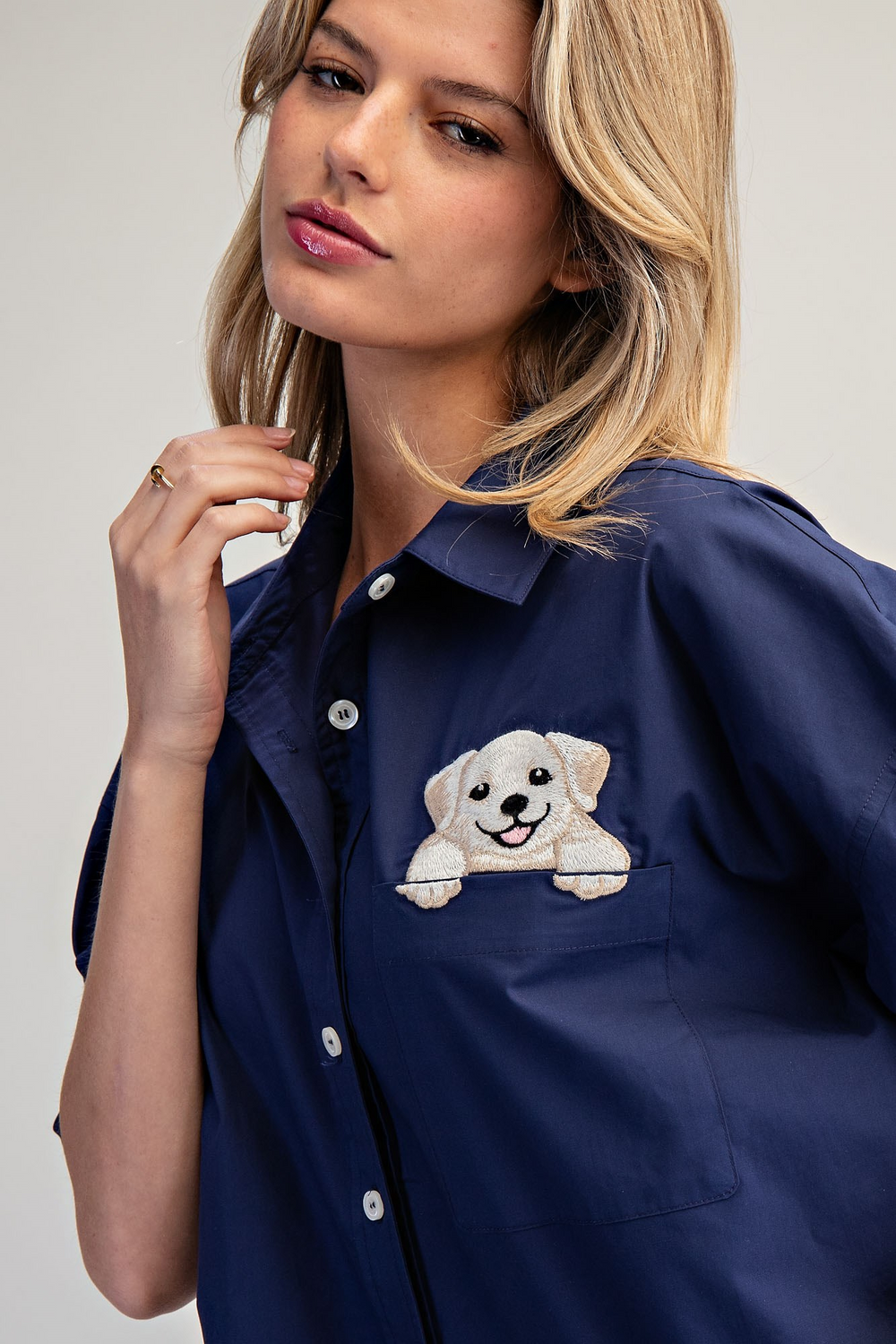 Woman wearing a navy blue shirt with a dog illustration on a plain background