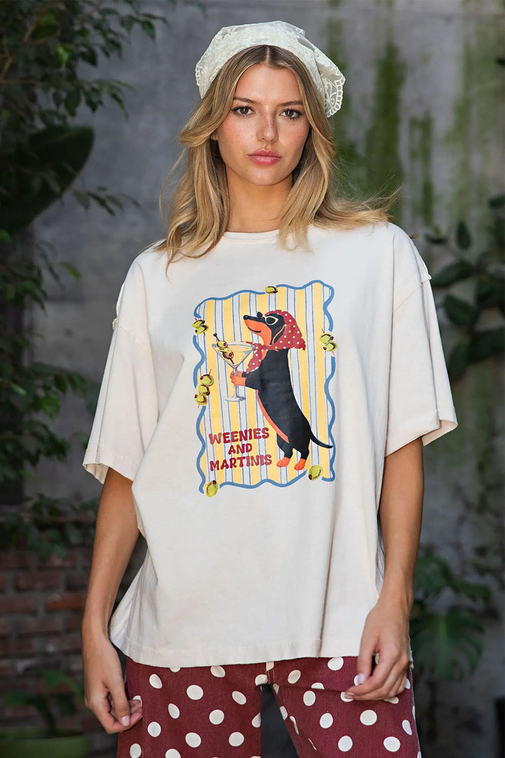 A woman wearing an oversized cream-colored graphic t-shirt with a &