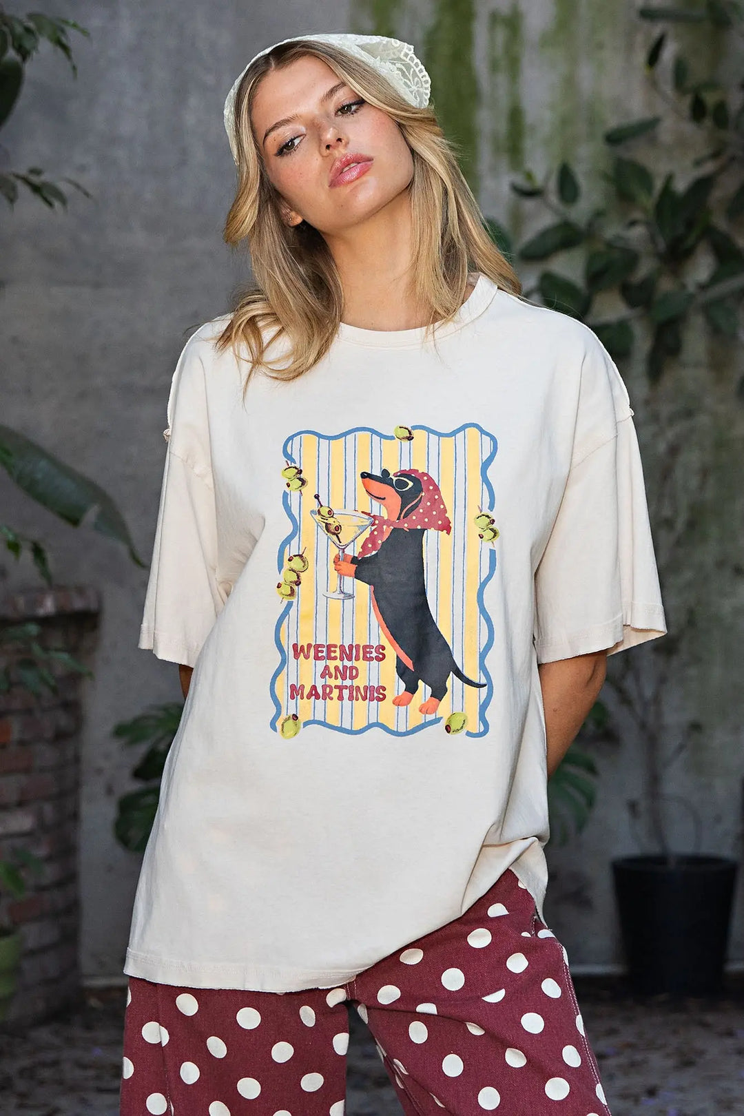 A woman wearing a cream-colored oversized graphic t-shirt with a &