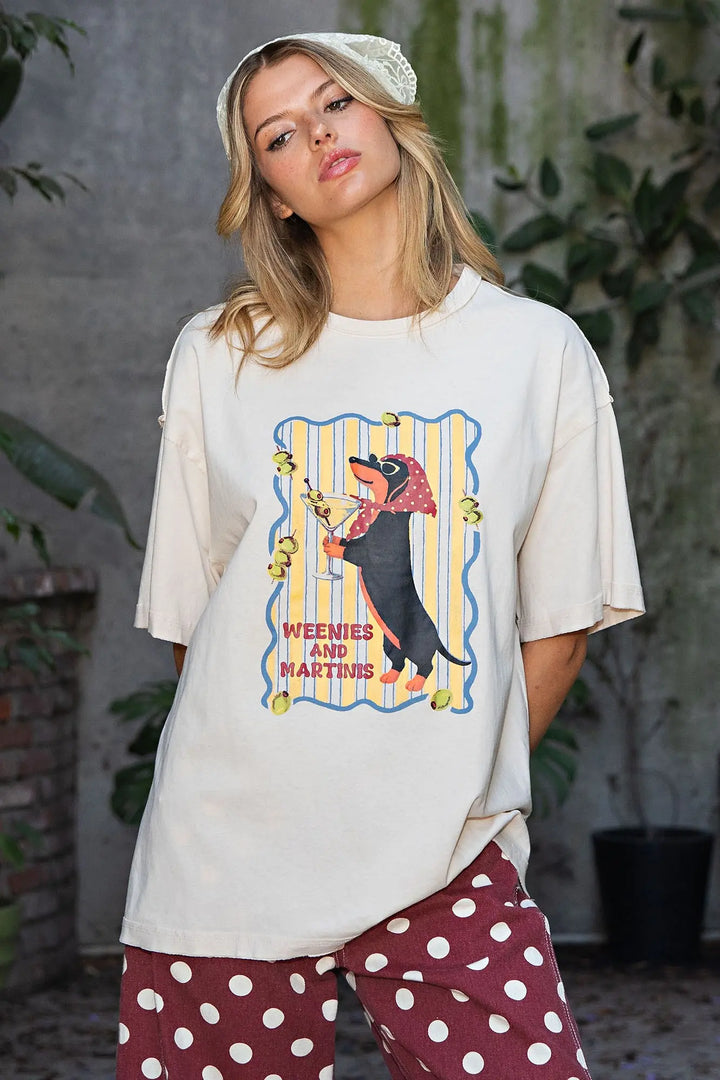 A woman wearing a cream-colored oversized graphic t-shirt with a &
