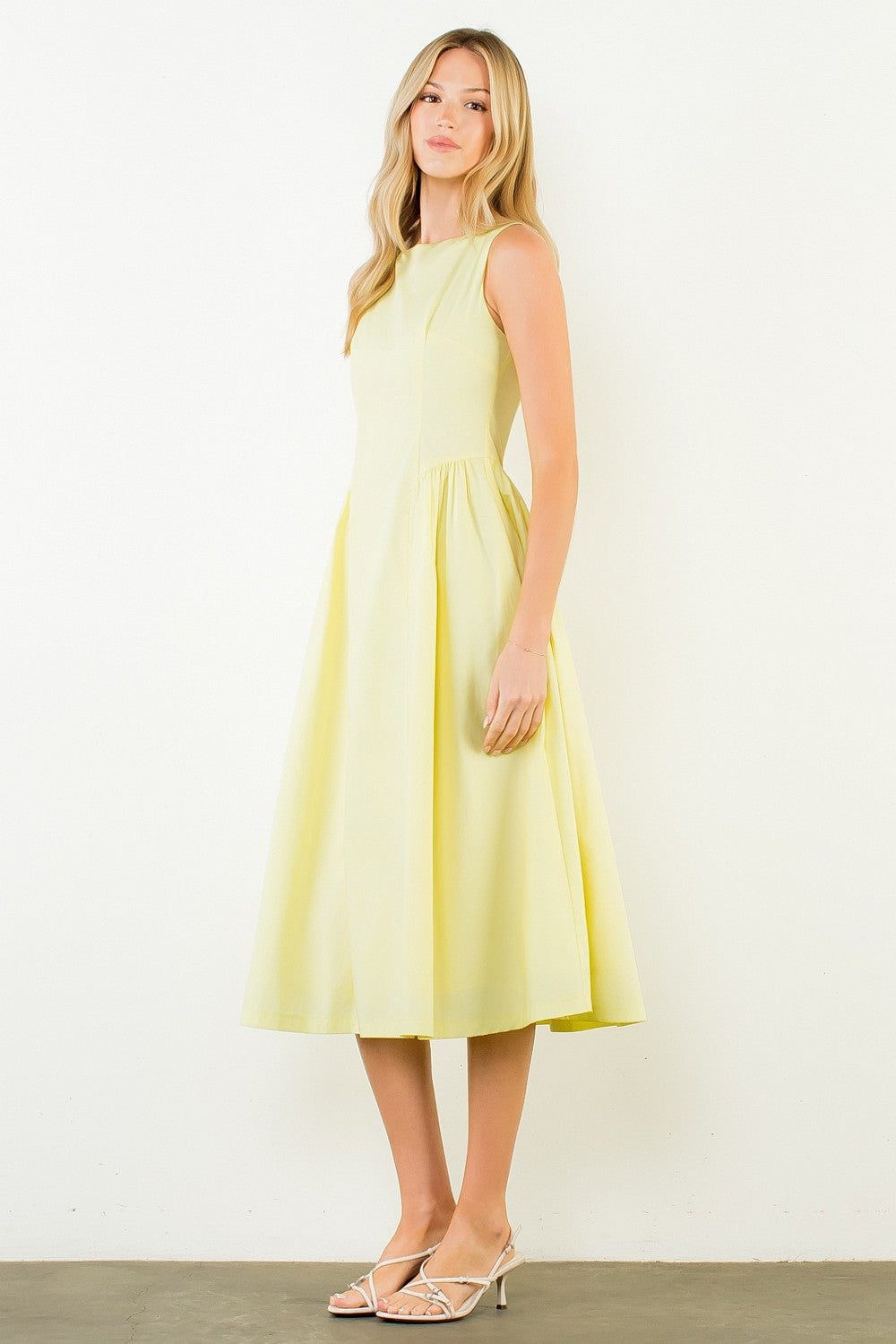 Woman wearing a light yellow dress against a white background