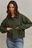 Woman wearing an olive green jacket with a brown collar against a neutral background