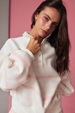 Woman wearing a white and pink striped sweater against a pink background