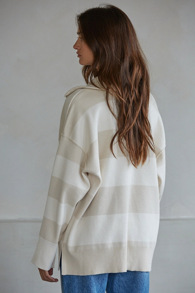 Woman wearing a beige and white striped sweater against a plain background