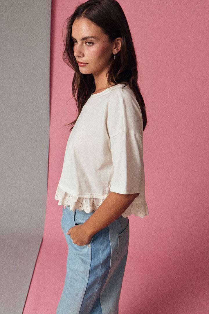 Woman wearing a white blouse and light blue jeans against a pink background