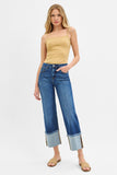 Woman wearing a yellow top and blue jeans on a white background