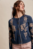 Woman wearing a blue sweater with floral patterns on a beige background