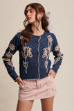 Woman wearing a blue cardigan with floral patterns on a beige background