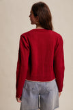 Person wearing a red sweater and light blue jeans on a beige background