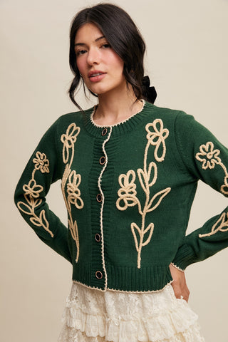 Woman wearing a green sweater with floral patterns on a beige background