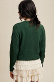 Person wearing a green sweater and white ruffled skirt on a beige background