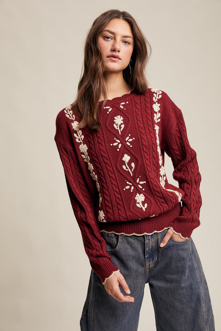Woman wearing a red sweater with white floral patterns on a beige background
