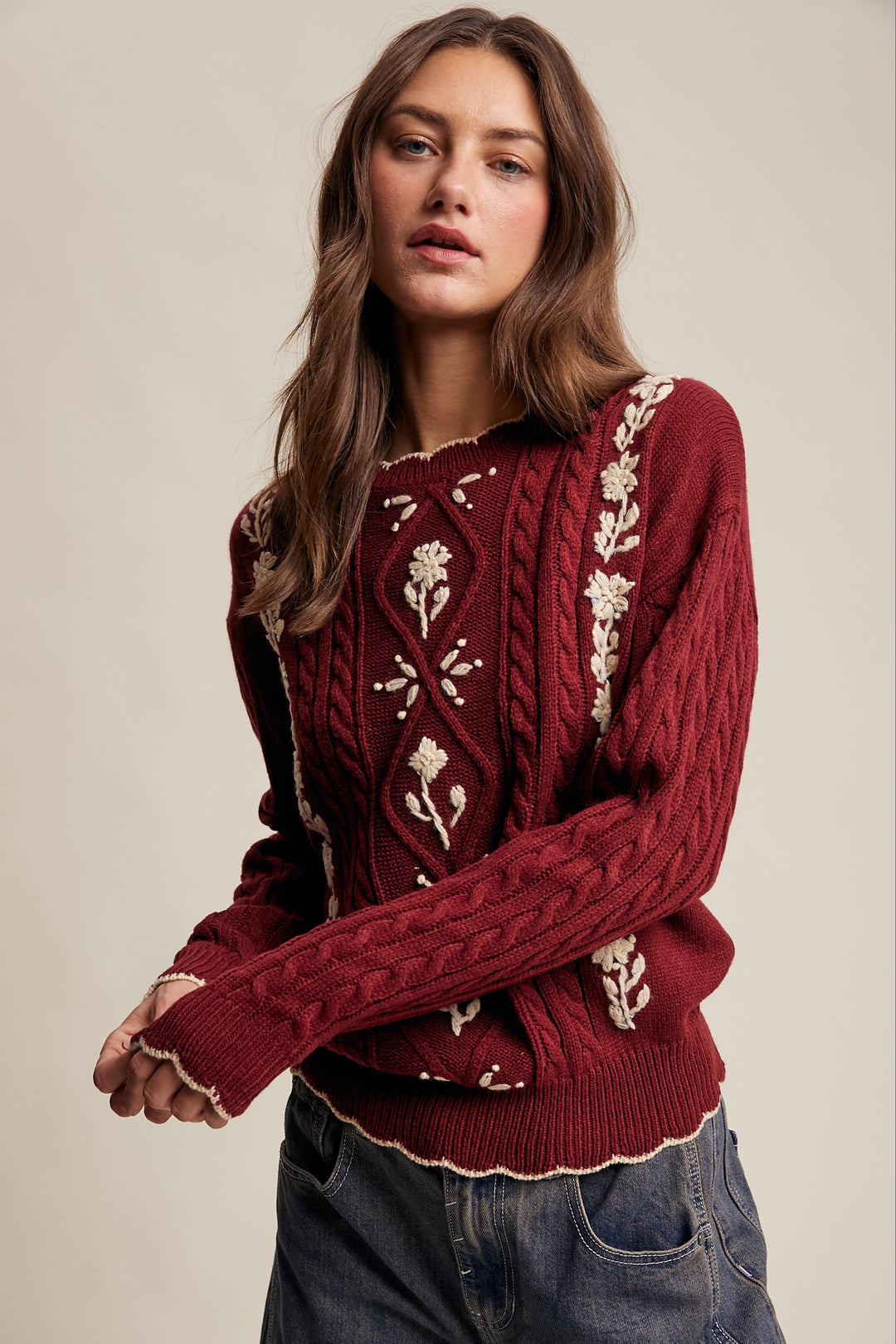 Woman wearing a red sweater with white patterns on a beige background