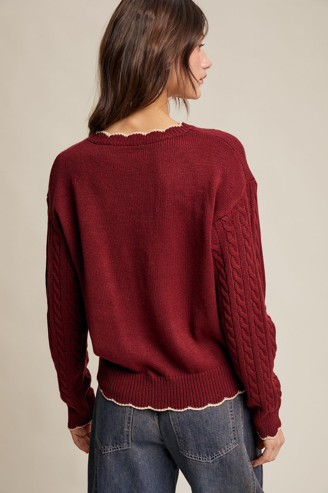 Woman wearing a maroon sweater with a beige background