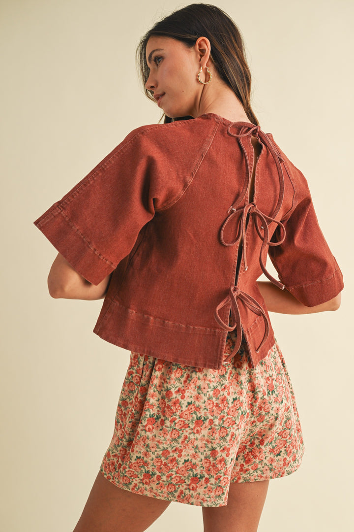 Woman wearing a rust-colored jacket and floral skirt on a beige background