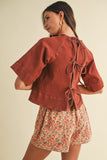 Woman wearing a rust-colored jacket and floral skirt on a beige background