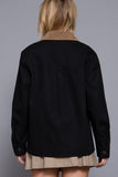 Person wearing a black jacket with a brown collar against a gray background