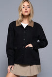 Woman wearing a black jacket with a brown collar against a gray background