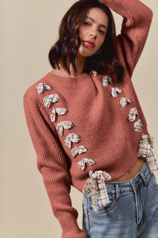 Woman wearing a pink sweater with decorative elements and blue jeans on a beige background