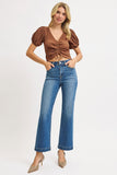 Woman wearing a brown top and blue jeans on a white background