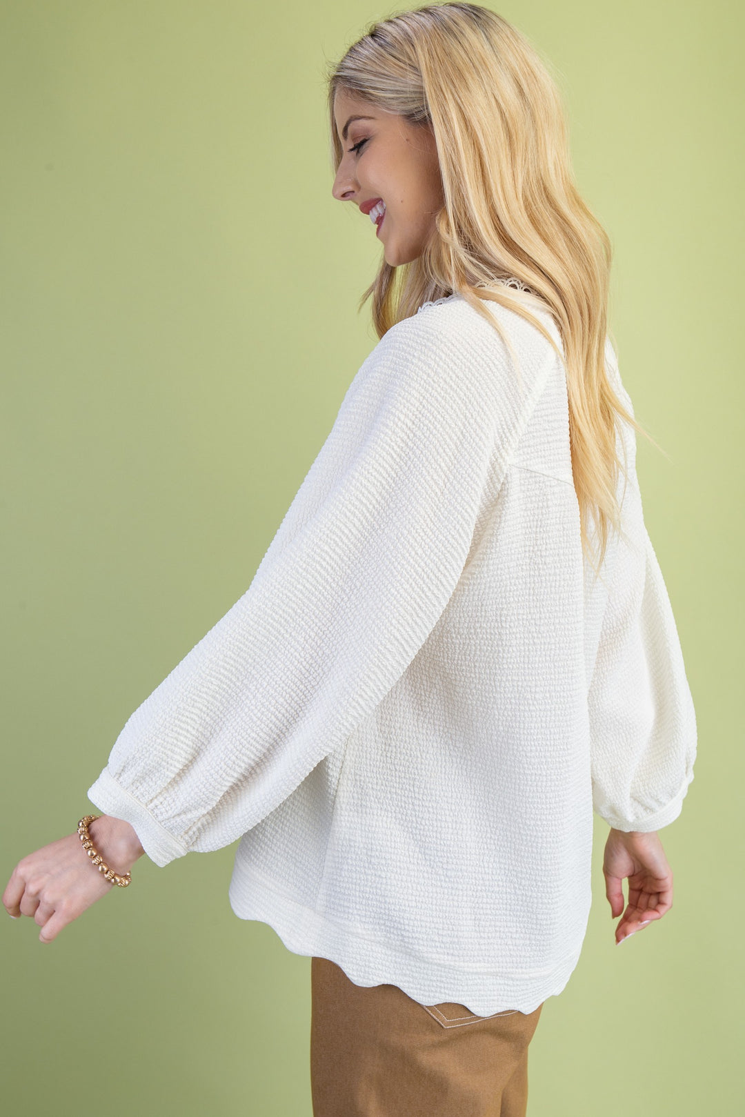 Woman wearing a white blouse with long sleeves against a green background