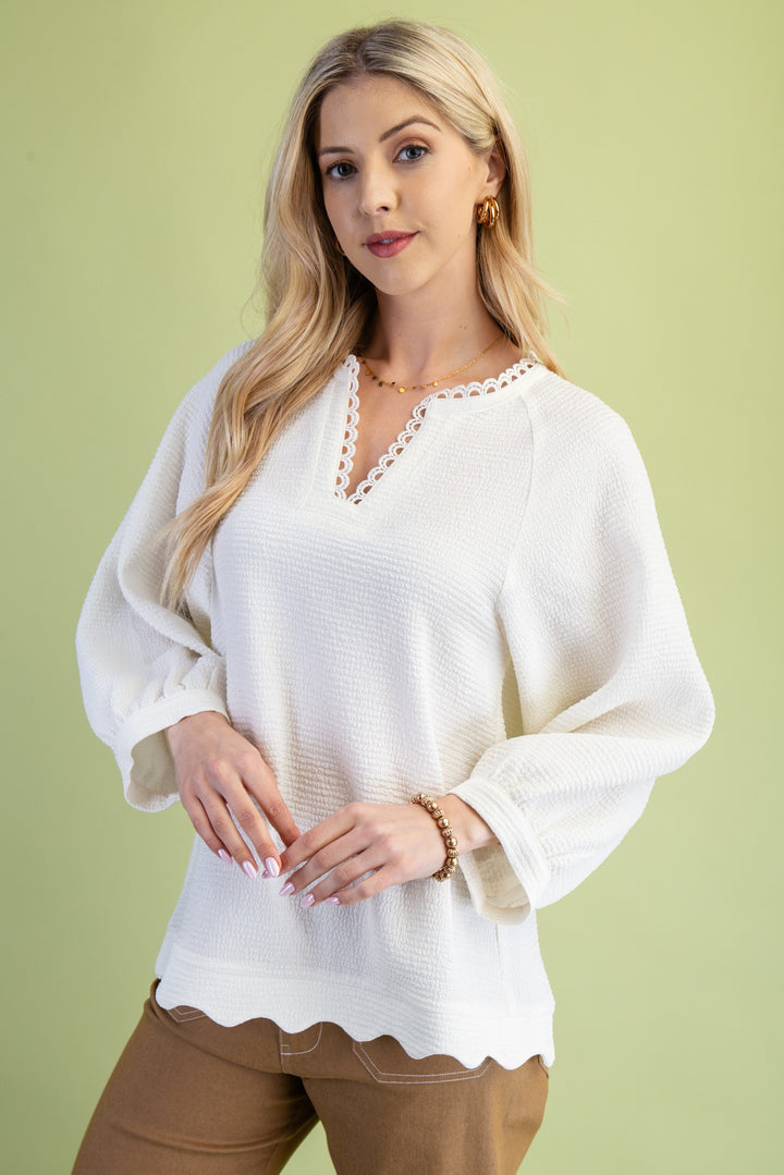Woman wearing a white blouse with scalloped edges on a green background