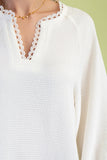 White sweater with lace detailing on a plain background