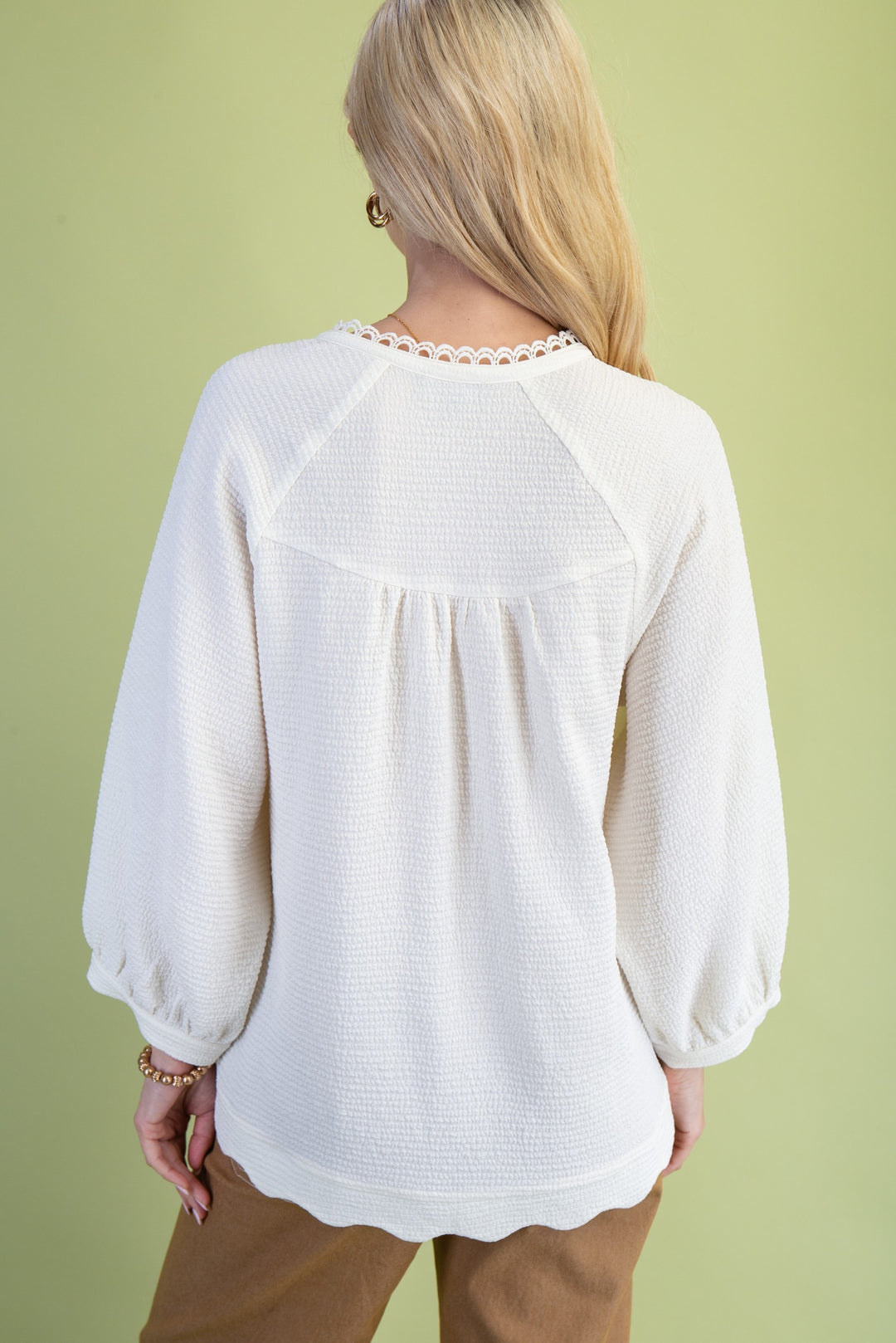 Person wearing a white blouse with a green background