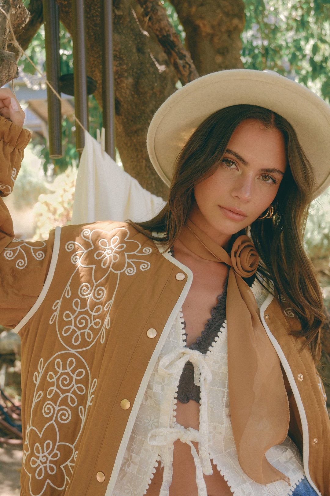 Woman wearing a beige hat and patterned cardigan in an outdoor setting