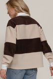 Person wearing a brown and beige striped sweater with a plain background