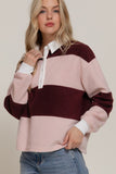 Woman wearing a color-blocked sweater with pink and burgundy sections on a plain background