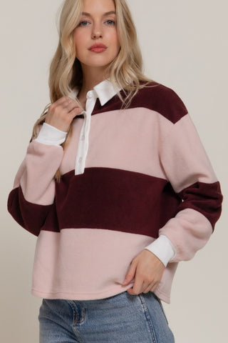 Woman wearing a color-blocked sweater with pink and burgundy sections on a plain background