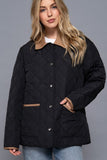 Woman wearing a black quilted jacket against a gray background