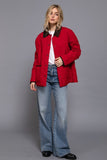 Person wearing a red jacket and blue jeans on a gray background