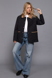 Woman wearing a black jacket, white shirt, and blue jeans on a gray background