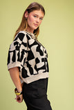 Woman wearing a black and white patterned sweater against a light green background
