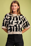 Woman wearing a black and white patterned sweater against a green background