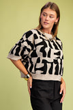 Woman wearing a black and white patterned sweater against a green background